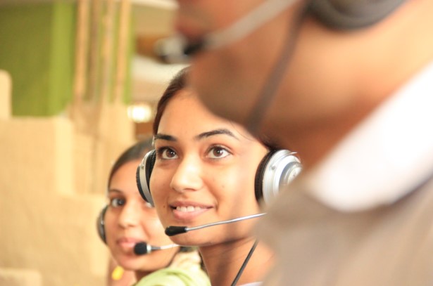 Employees wearing headsets, working in a call center environment, using digital platforms to meet customer service expectations