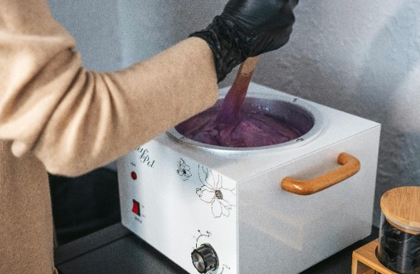 Esthetician mixing wax in a wax warmer
